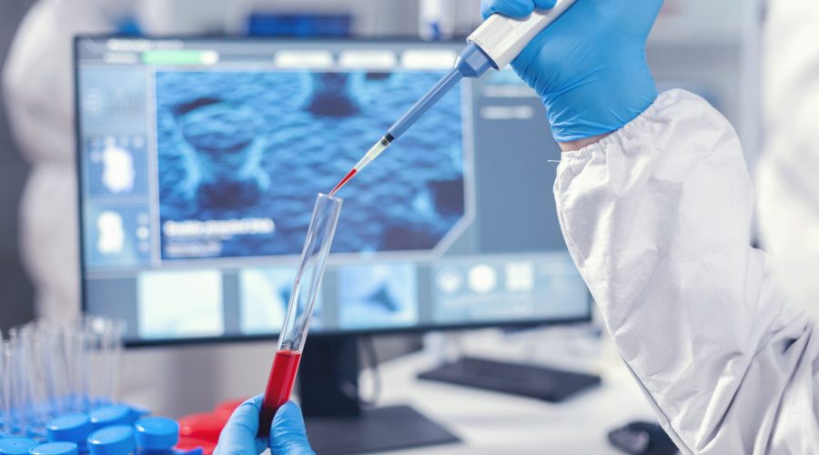 Medical researcher dripping blood into a test tube from a micropipette. Doctor working with various bacteria and tissue, pharmaceutical research for antibiotics against covid19.